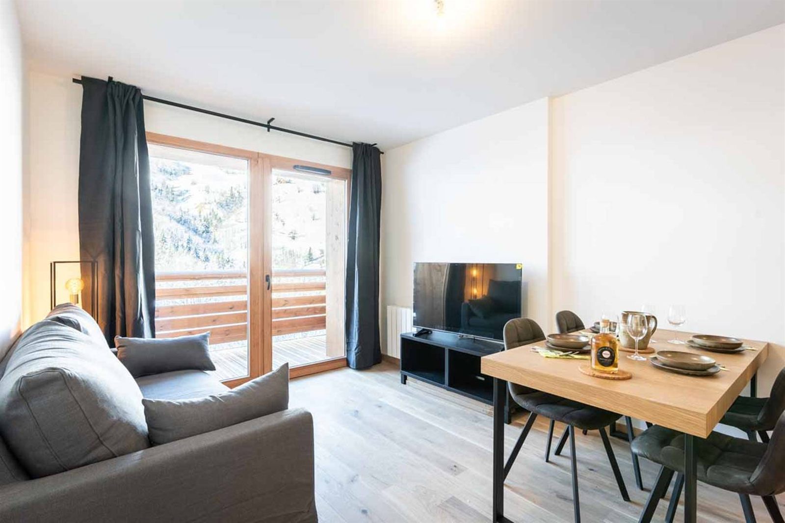 Le séjour : canapé, coin repas et grande baie vitrée sur le balcon